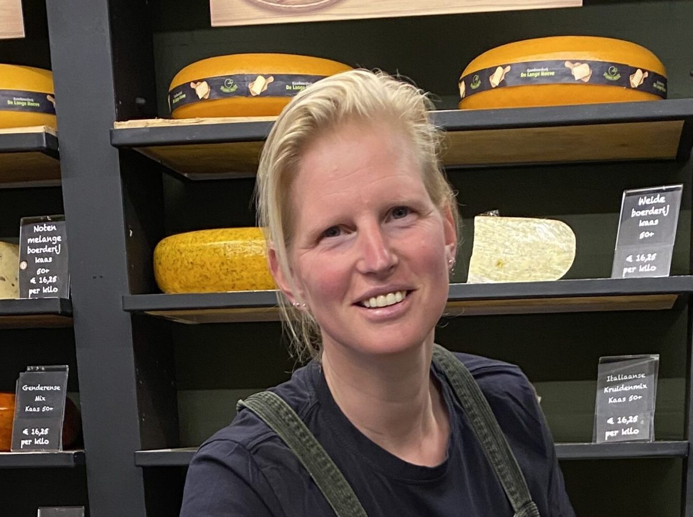 Danielle in de kaaswinkel van Kaasboerderij De Lange Hoeve, omringd door ambachtelijke kazen.
